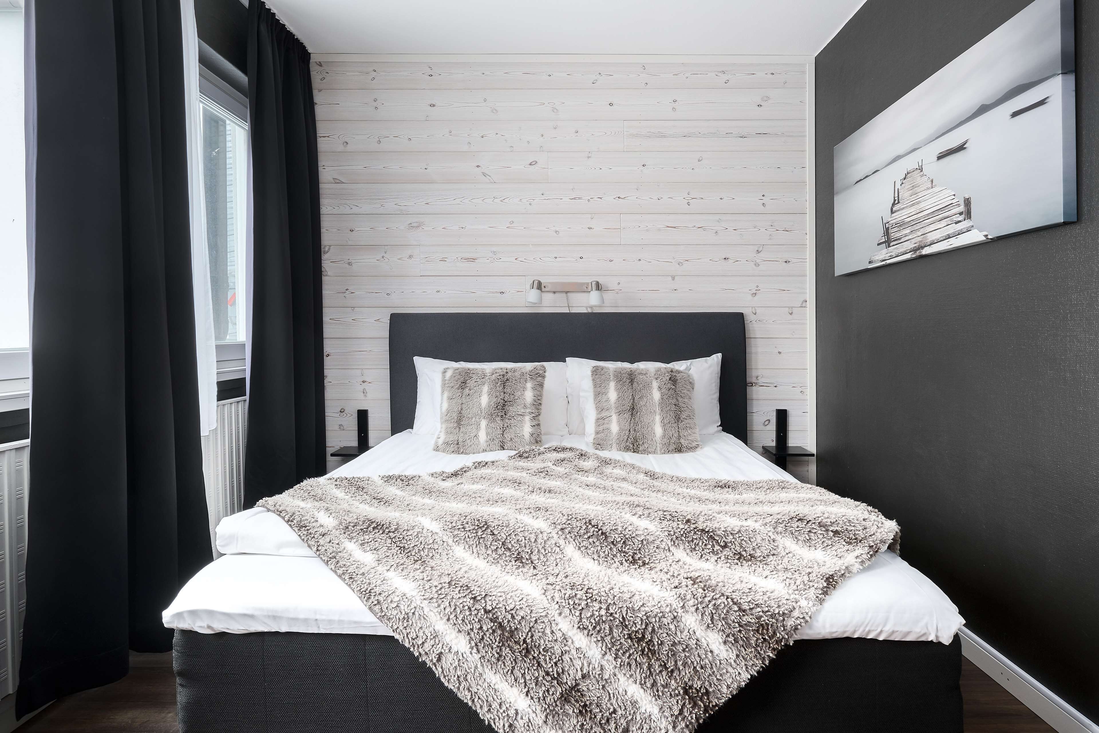 Un dormitorio moderno con un panel de madera en la pared, una cama grande con un edredón mullido y un cuadro sobre la cama.