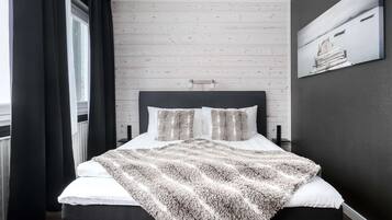 Un dormitorio moderno con un panel de madera en la pared, una cama grande con un edredón mullido y un cuadro sobre la cama.