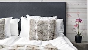 A neatly made bed with white and patterned pillows, a dark headboard, and a small potted orchid on a nightstand. - Sure Hotel by Best Western Algen (Östersund)