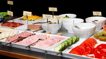 A buffet with various food options including meats, cheeses, and fruits.