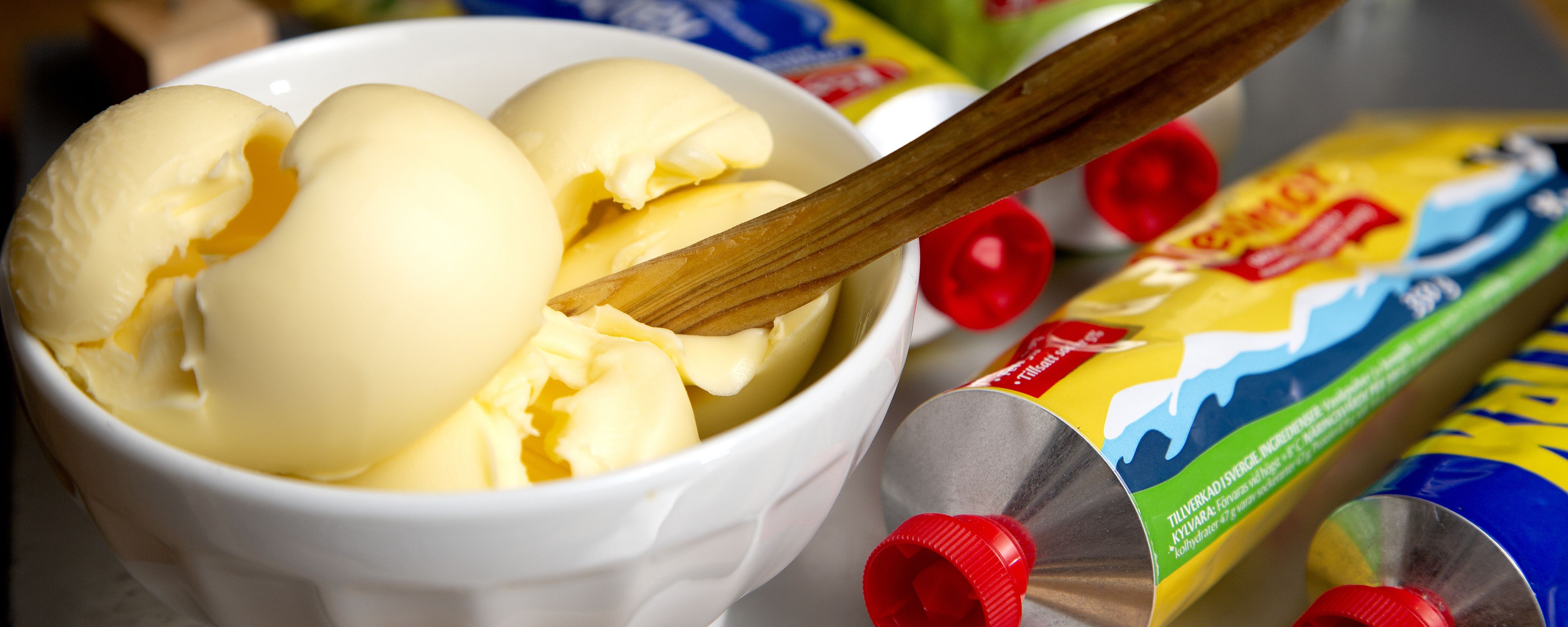 A bowl of ice cream with a wooden spoon, surrounded by colorful packaging.