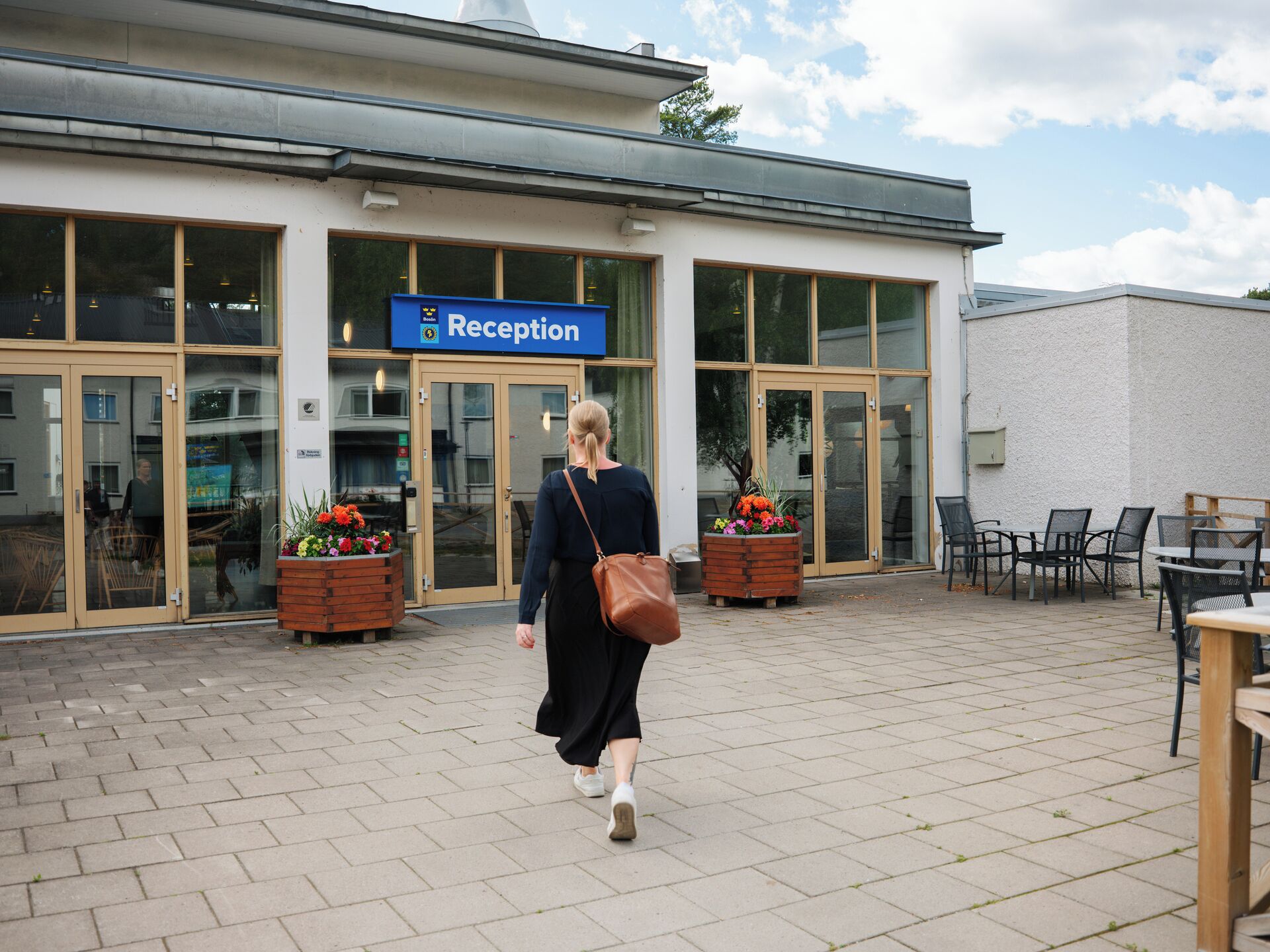 En byggnad med en reception, stora fönster och sittplatser utomhus.