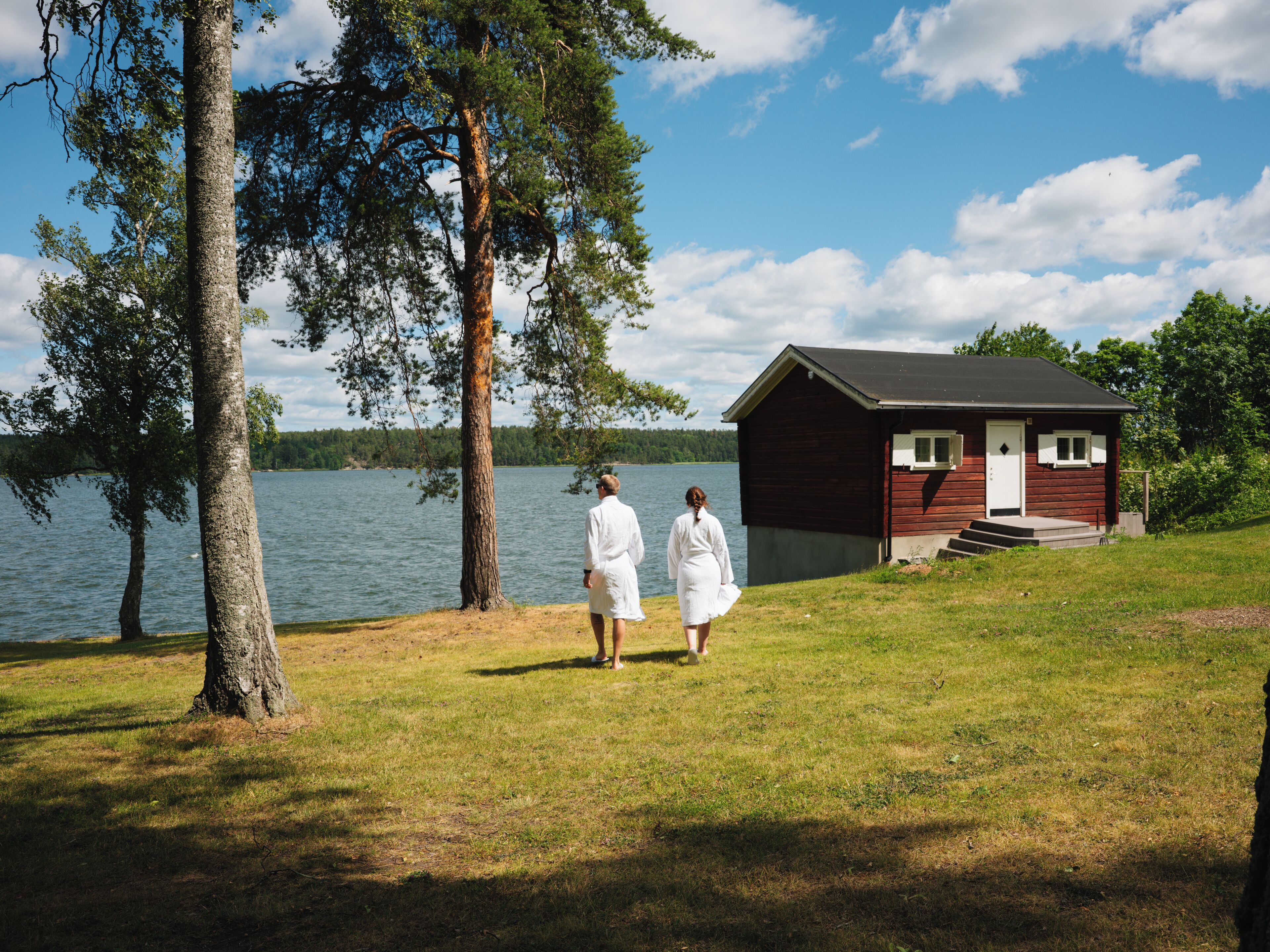 A cabin by a lake with a grassy area and trees.