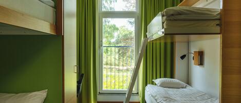 Un dormitorio con literas, una ventana con cortinas y vistas a zonas verdes.