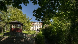 A historic building with a central tower and a symmetrical facade, surrounded by lush greenery and trees. - Bosön Hotell & Konferens (Lidingo)