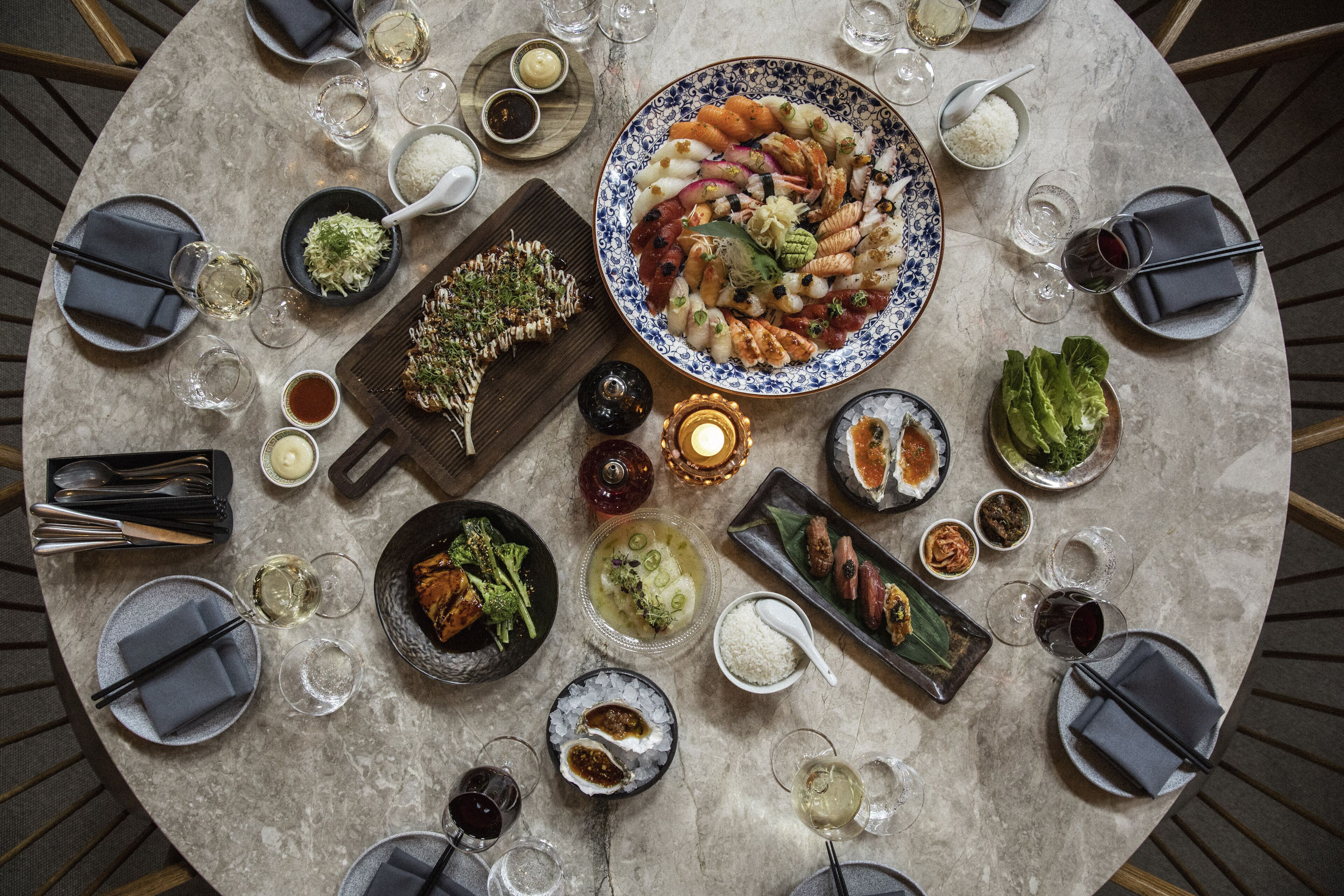 A round table with various dishes, glasses, and cutlery, suggesting a dining setup.