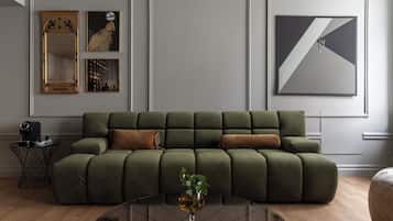 A modern living room with a green sectional sofa, a coffee table, and framed artwork on the wall.