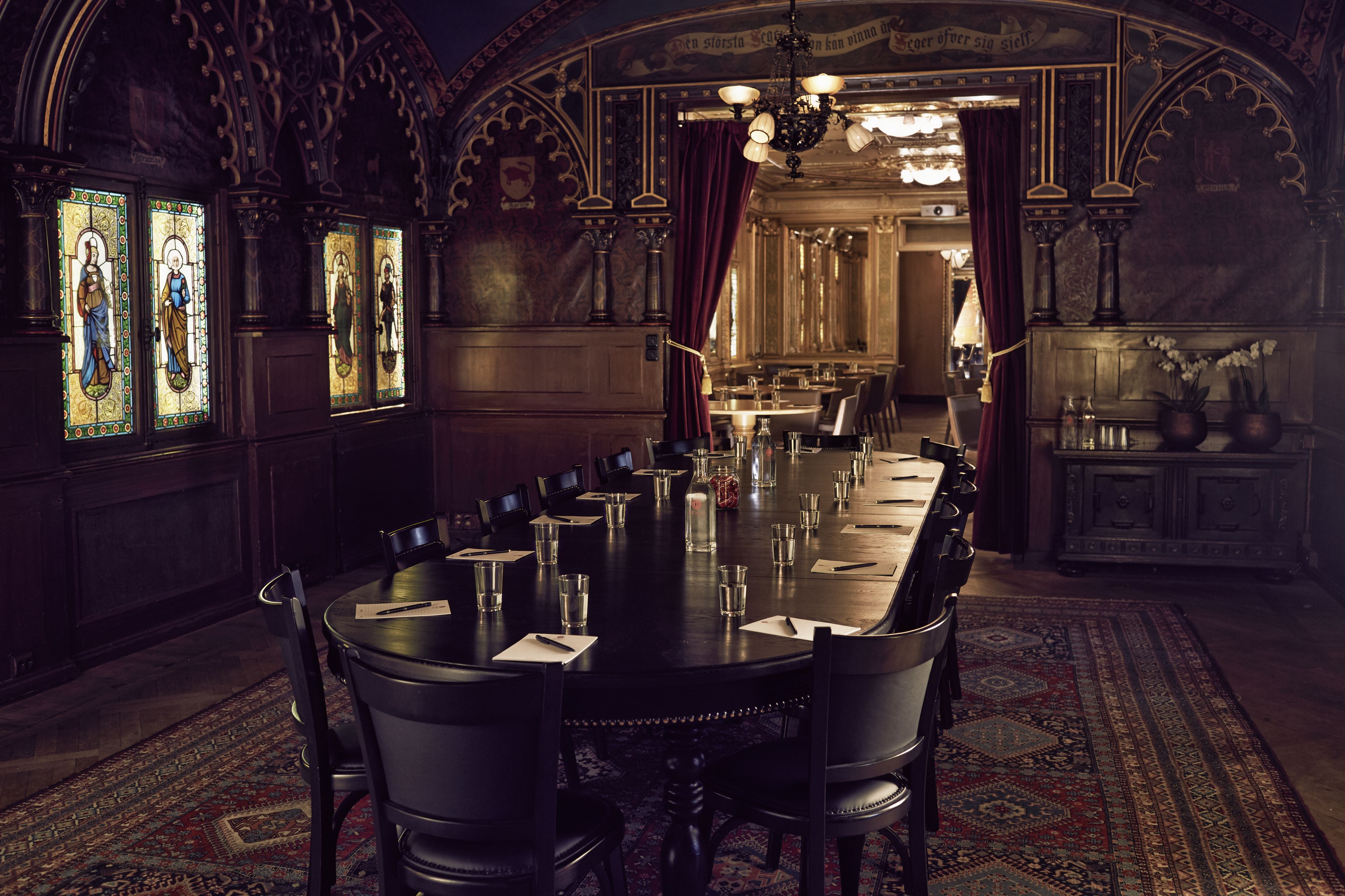 A formal dining room with a long table set for a meal, surrounded by chairs.