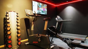 A gym with a treadmill, stationary bike, and dumbbells.