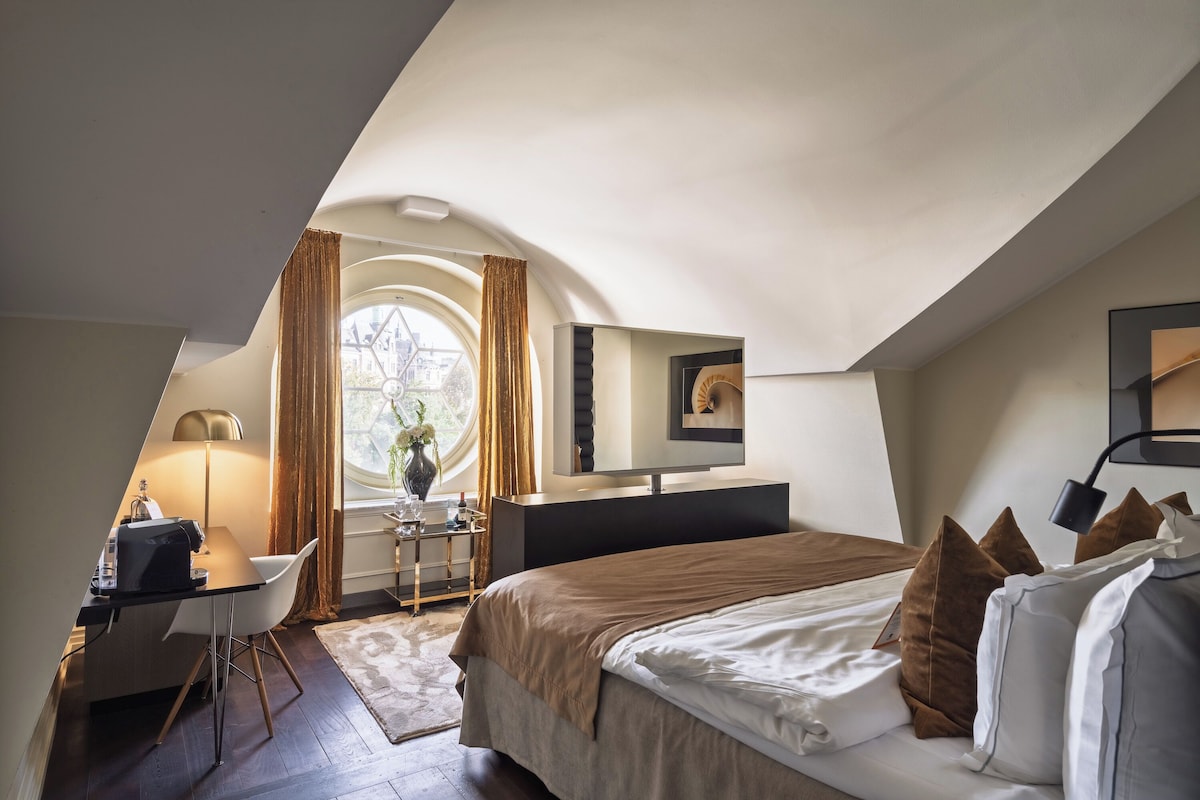 Un dormitorio moderno con una cama grande, un escritorio y un ventanal con cortinas.