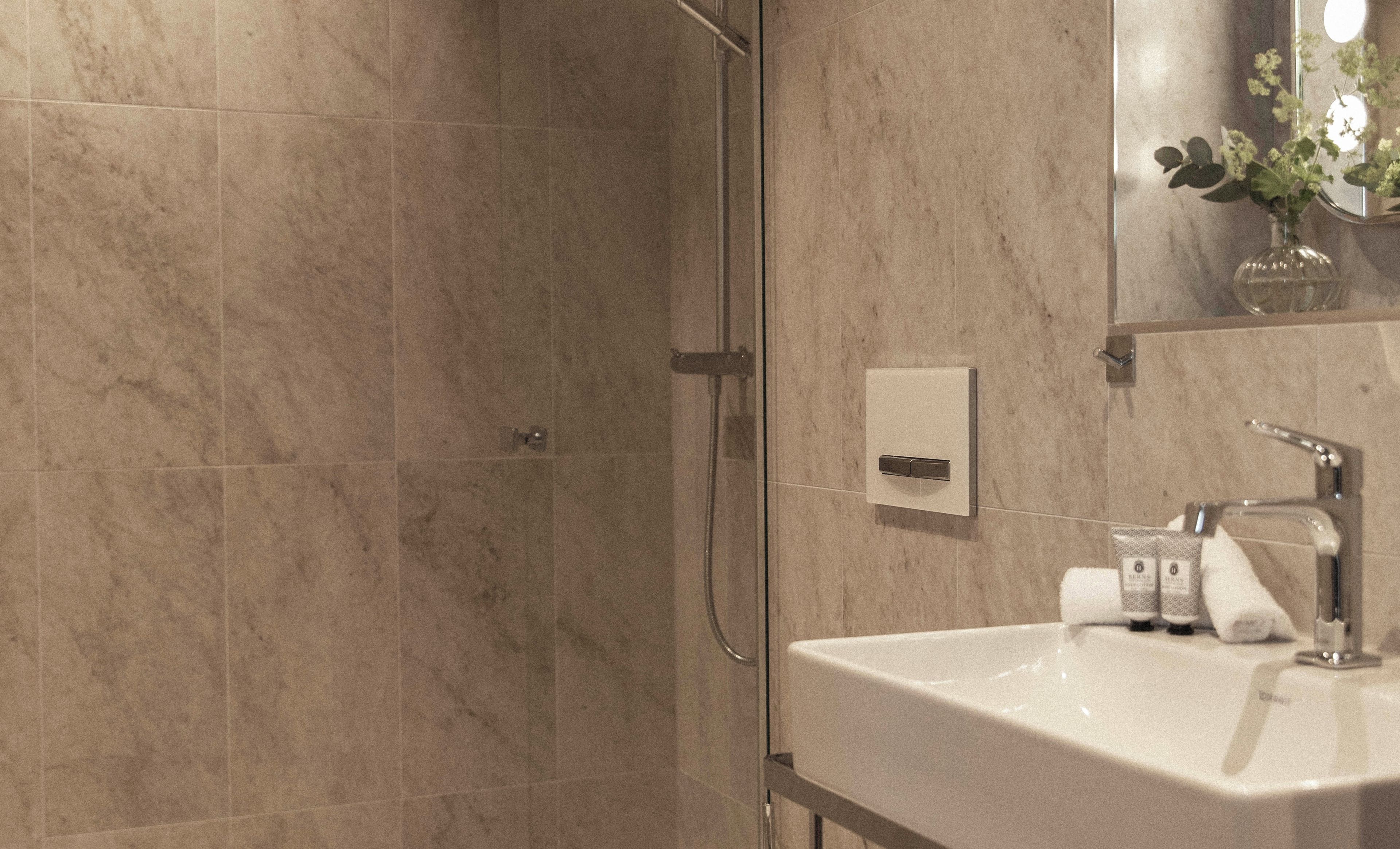 Une salle de bain avec une douche, un lavabo et un miroir.