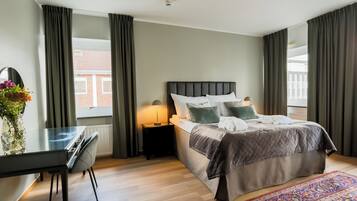 Una habitación de hotel moderna con una cama grande, un escritorio y vistas al exterior.