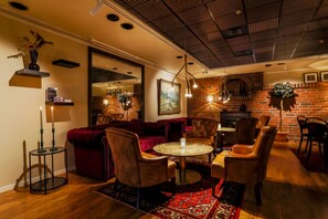 A cozy living room with a brick fireplace, leather chairs, a round coffee table, and a red rug.