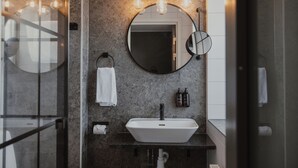 A modern bathroom with a round mirror, a white sink, and a towel rack.
