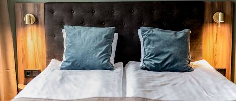 A neatly made bed with a tufted headboard, two pillows, and bedside lamps.