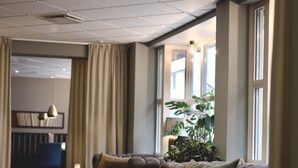 Un área de estar moderna con sofás de cuero, piso de madera y un gran ventanal que proporciona luz natural.