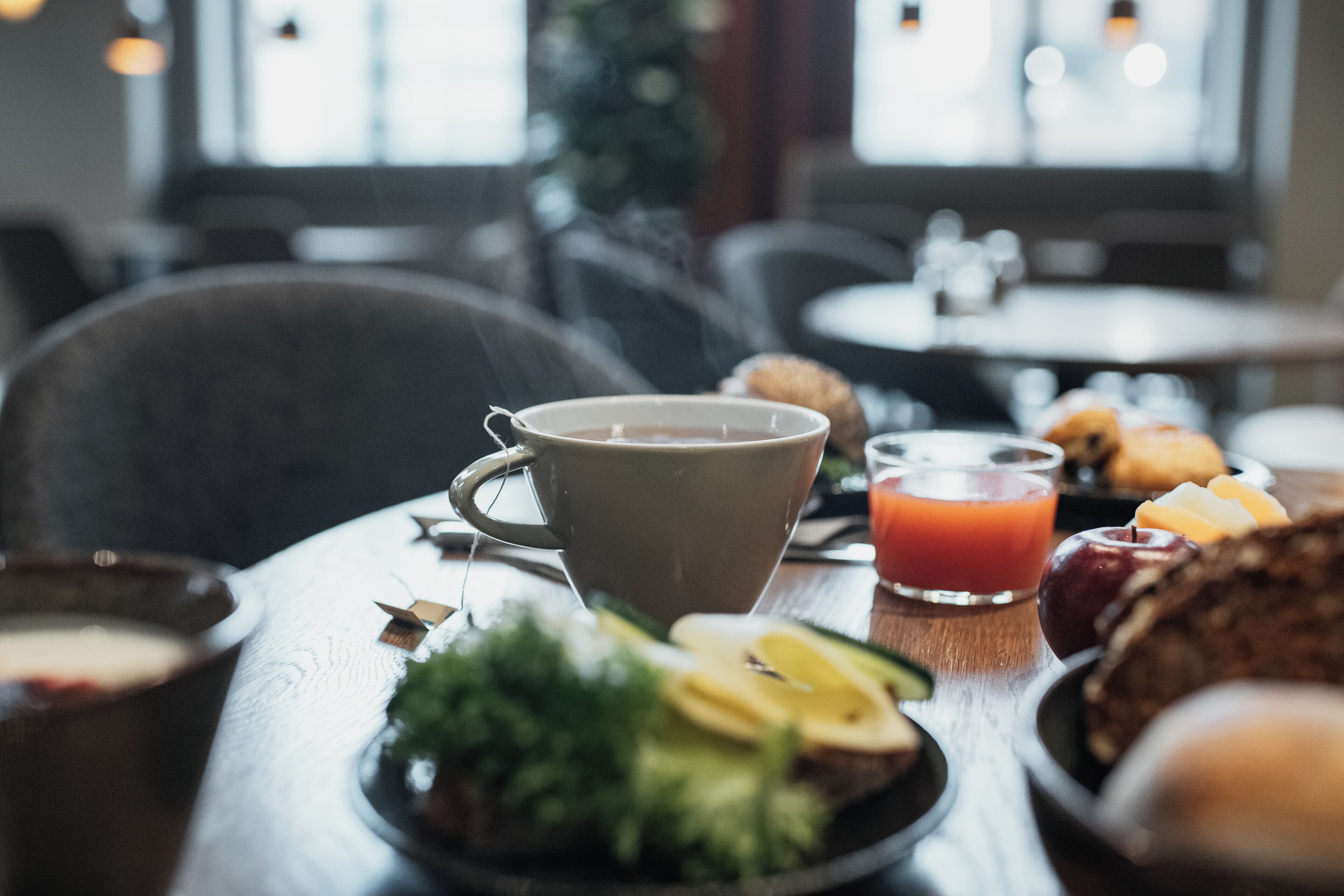 A breakfast setting with a cup of coffee, a glass of orange juice, and a plate with fruits and pastries.