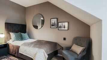 A bedroom with a bed, a chair, a mirror, and two framed pictures on the wall.