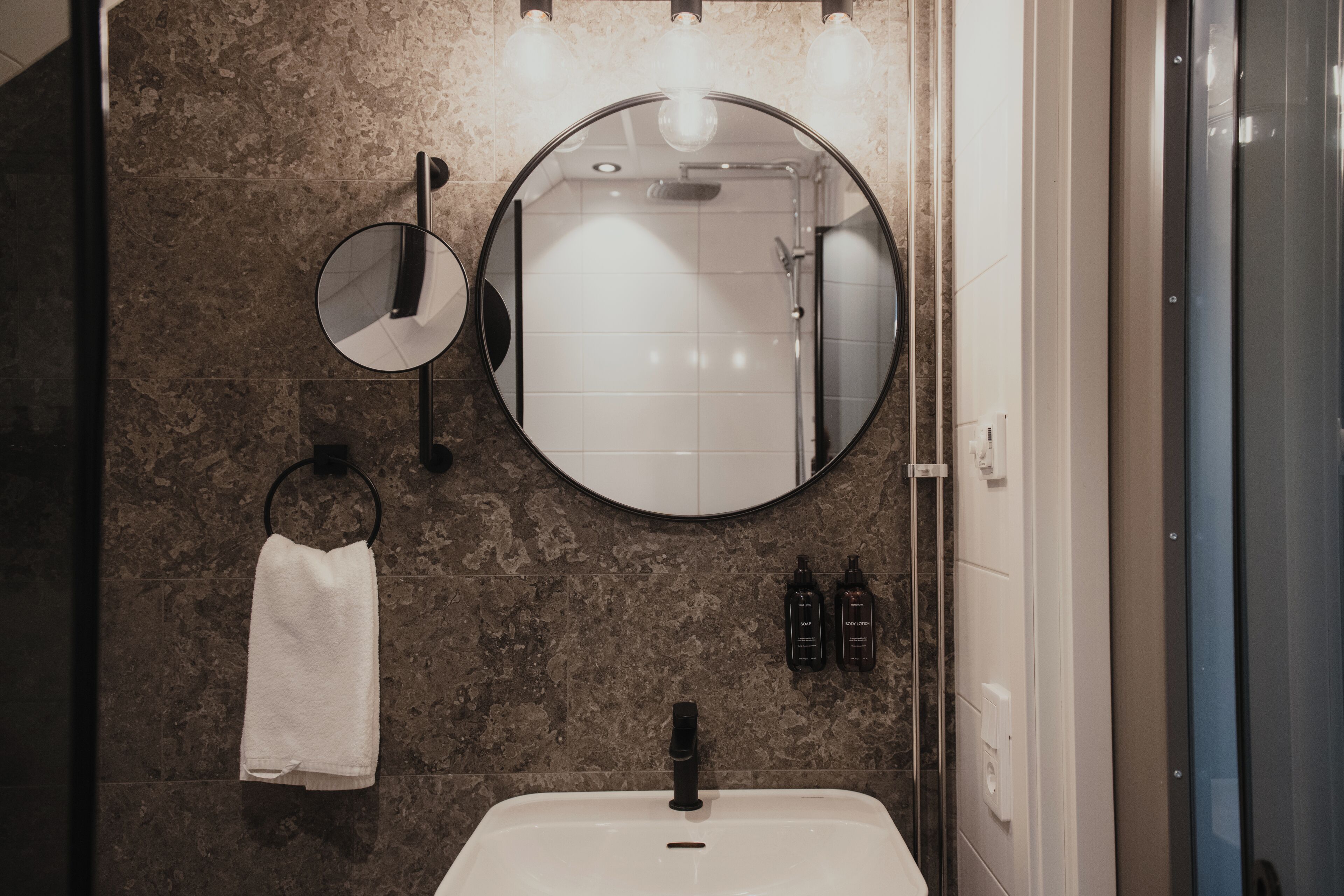 Ein Badezimmer mit rundem Spiegel, Handtuchhalter und Waschbecken.