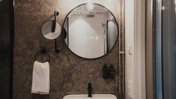 Ein Badezimmer mit rundem Spiegel, Handtuchhalter und Waschbecken.