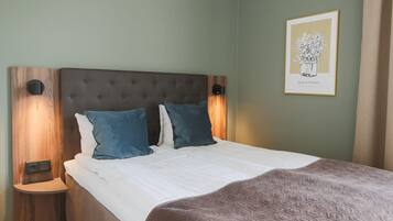 A neatly made bed with a brown headboard, two blue pillows, and a patterned blanket.