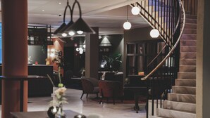 Un hall d’hôtel moderne avec un escalier en marbre, un espace salon et un bar.