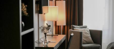 A modern hotel room with a desk, chair, and a large window with curtains.