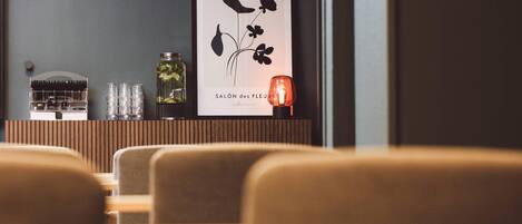 A framed artwork titled 'SALÔN des FLEURS' on a wall, a glass jar with a plant, and a candle on a wooden shelf.