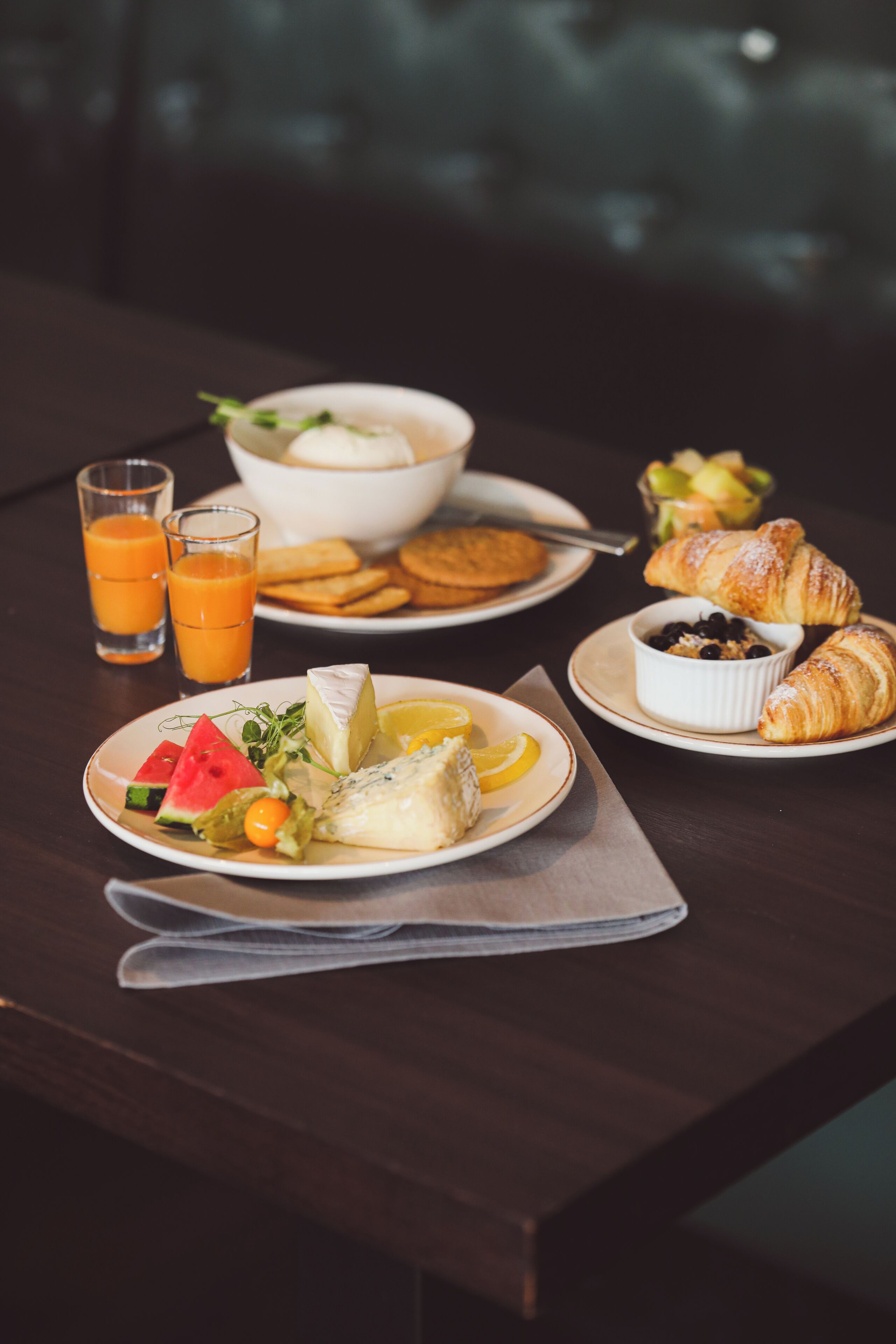 A breakfast setting with plates of food, glasses of orange juice, and a croissant.