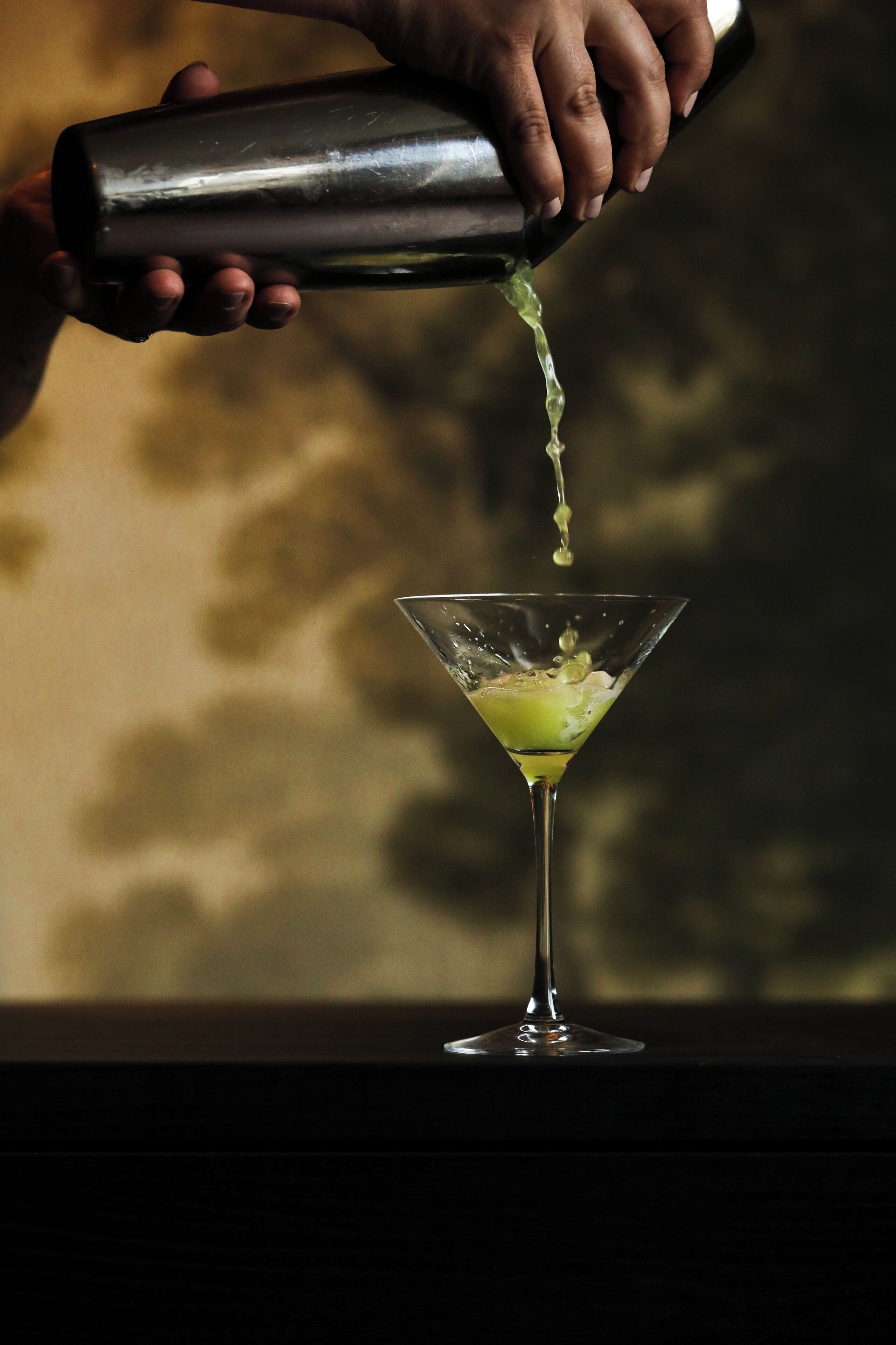 Una mano sirviendo una bebida en una copa de martini.