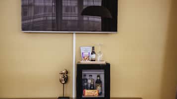 Un mini-bar surmonté d’un téléviseur, une petite statue et un réfrigérateur contenant des boissons et des en-cas.