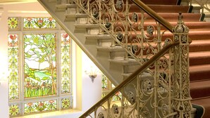 Una gran escalera con barandales de metal ornamentados y un suelo a cuadros.