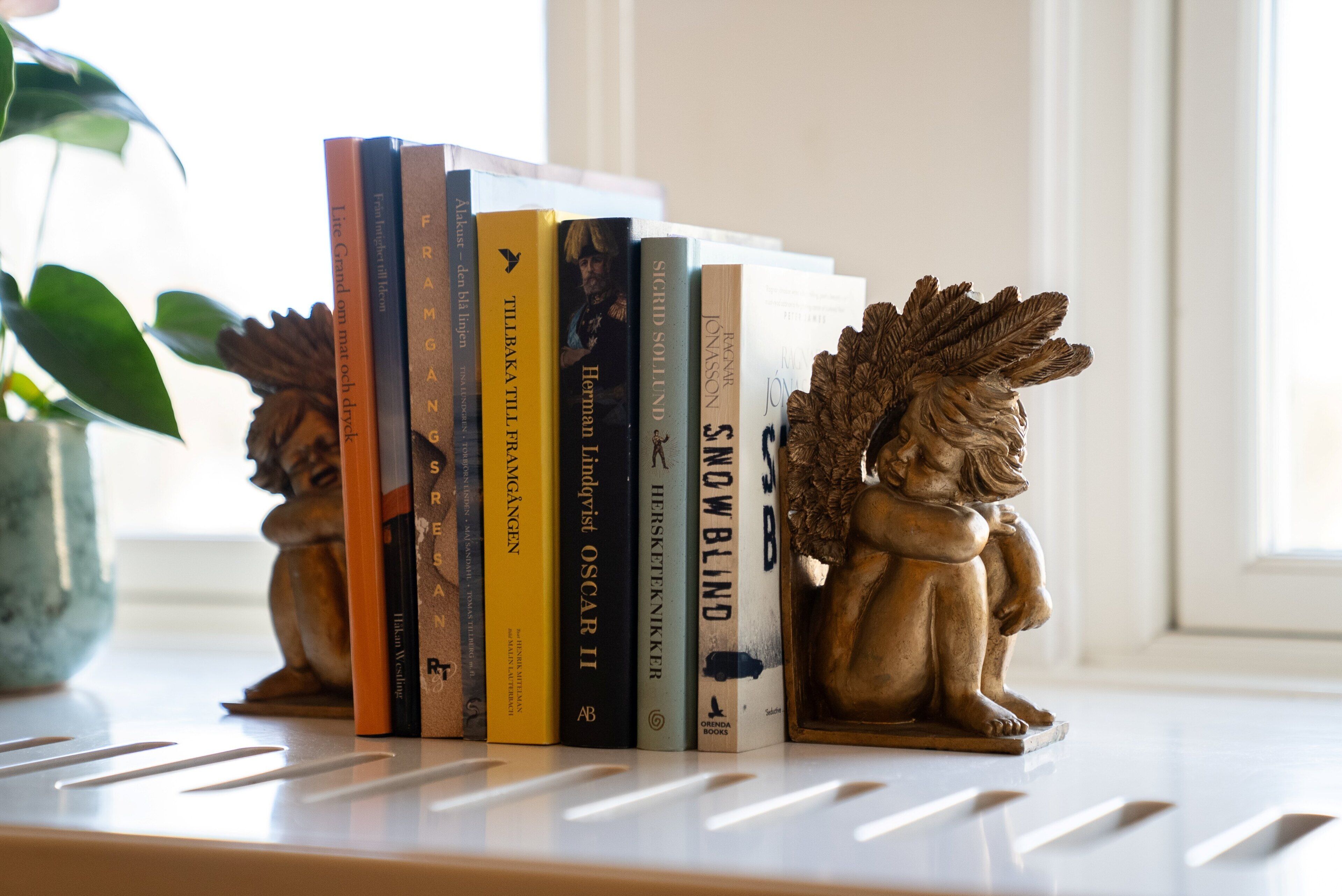 Een boekenplank met boeken en twee decoratieve engelbeeldjes.