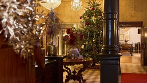 Un lobby espacioso con un gran árbol de Navidad, candelabros elegantes y un piso a cuadros.