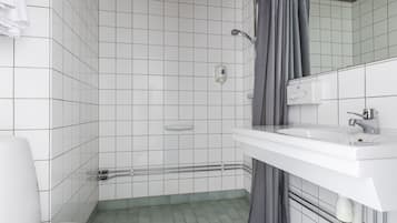 A bathroom with white tiled walls, a white sink, and a shower area.