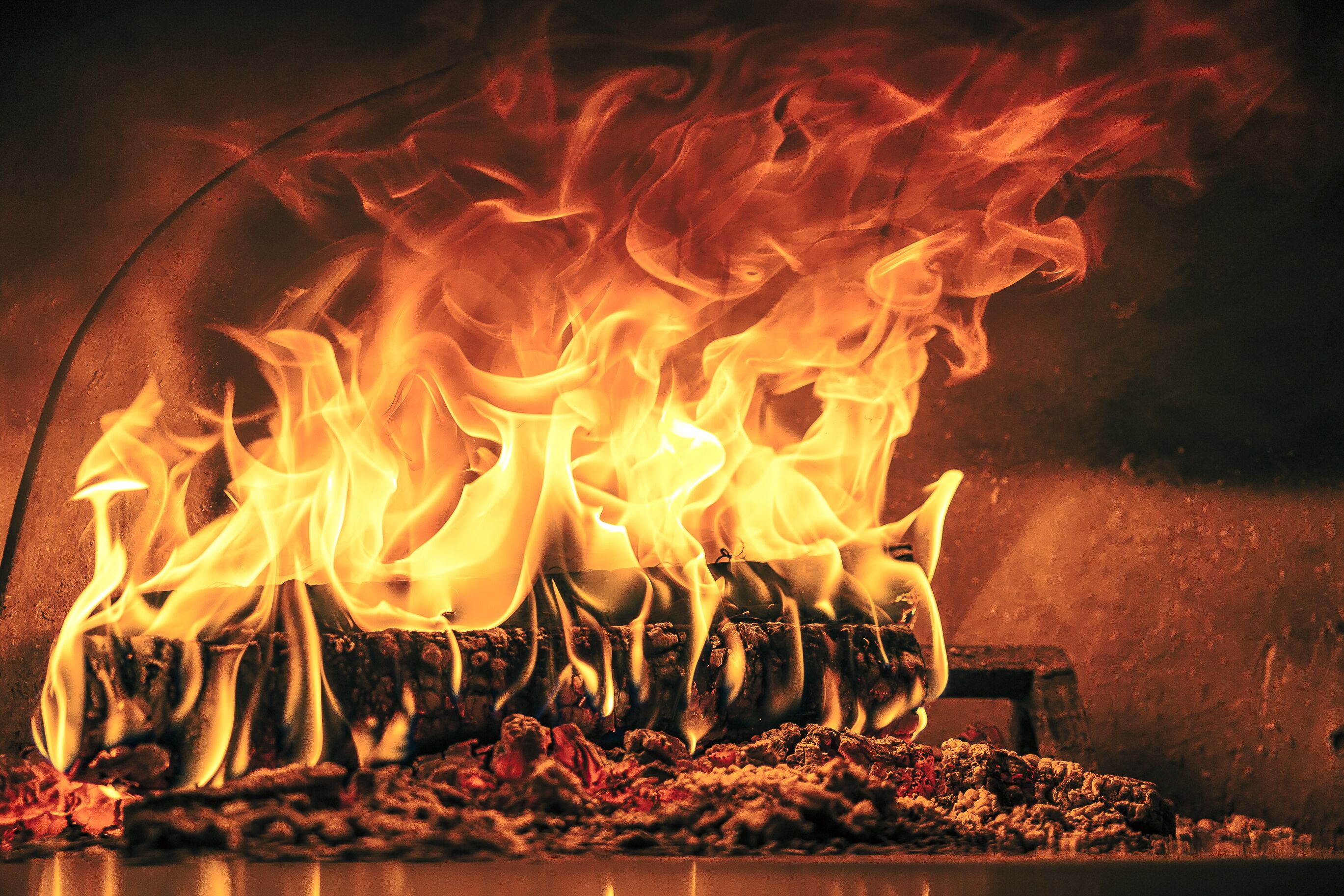 A fire burning in a fireplace with logs and embers visible.