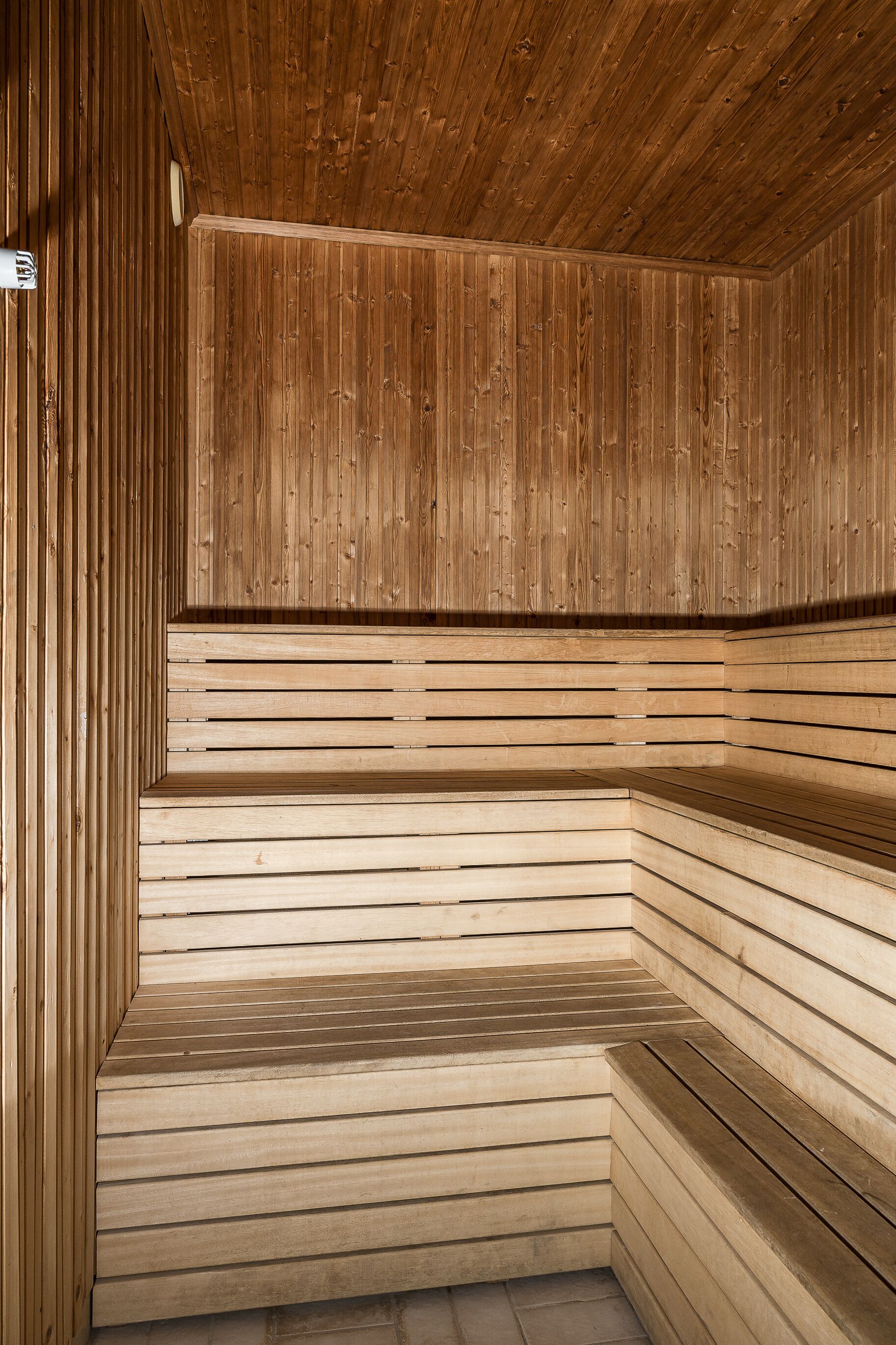 Una sauna con listones de madera en las paredes y el techo, y una zona de bancos.