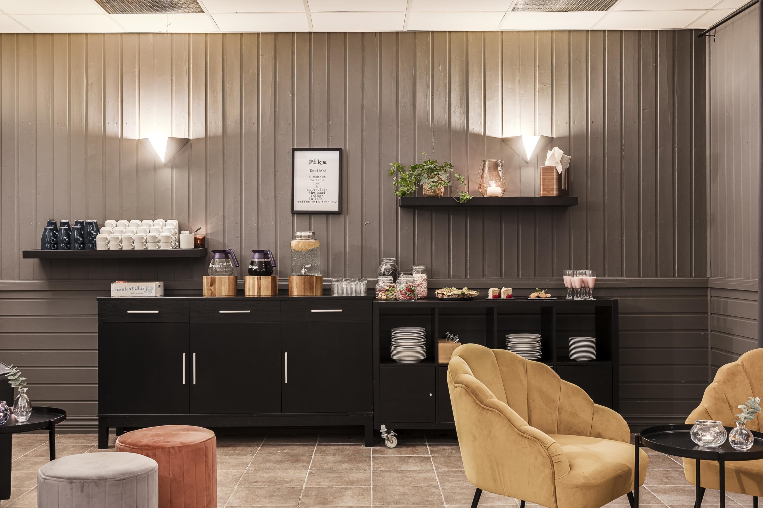 A modern kitchen with a black cabinet, a coffee station, and two chairs.