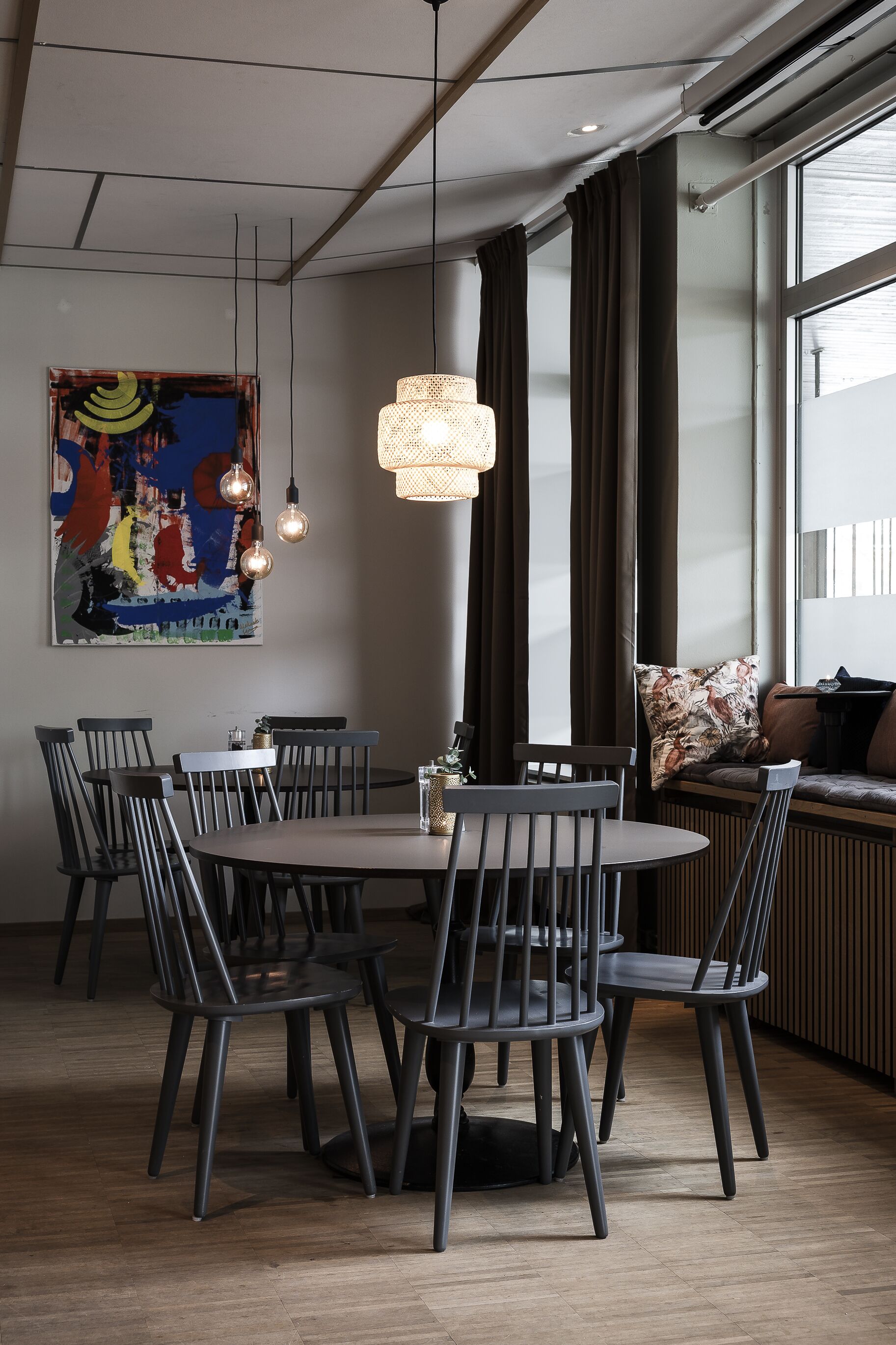 Un espace repas moderne avec une table ronde, des chaises foncées et un luminaire suspendu.