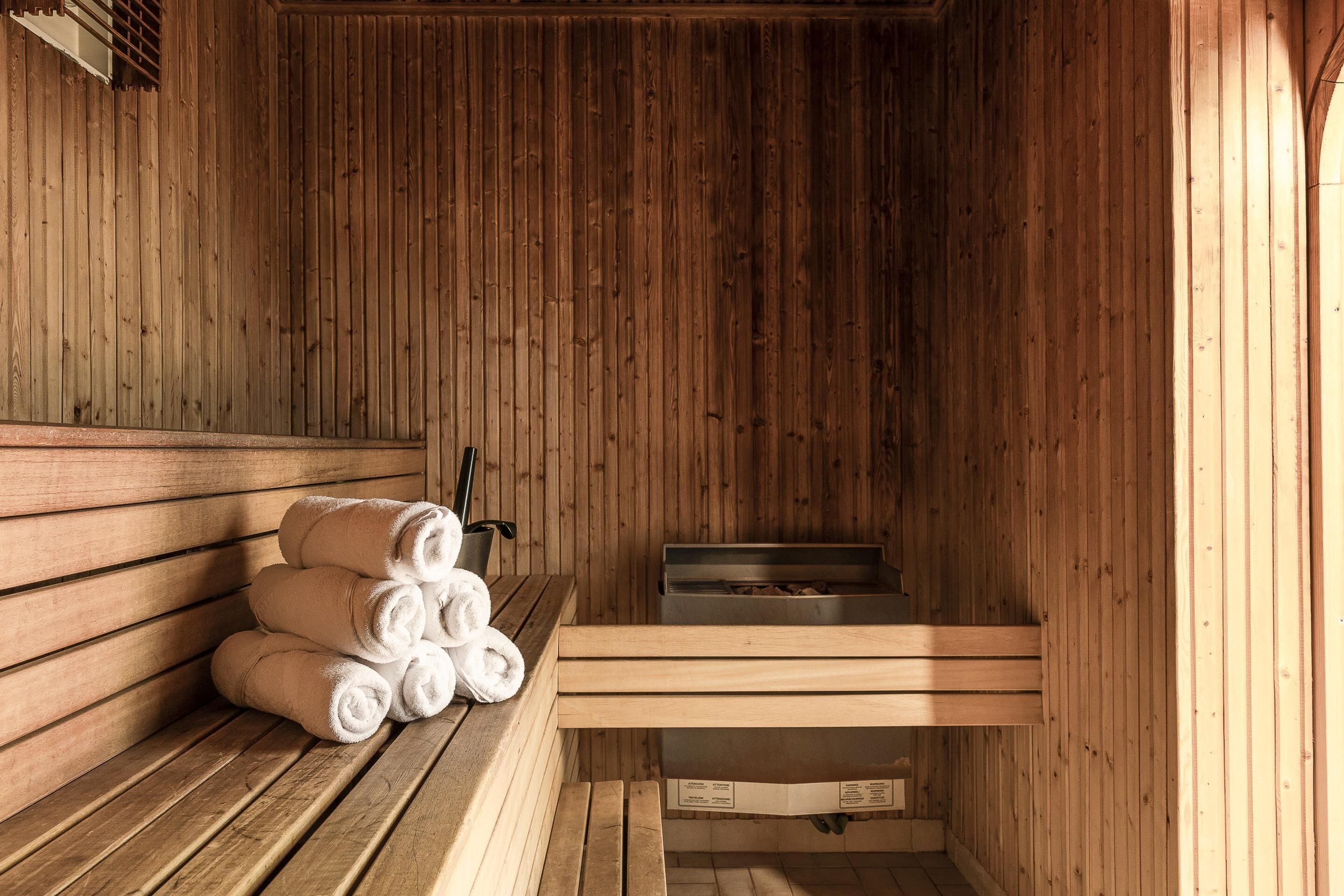 A sauna with wooden benches, a towel rack, and a steam room.