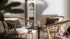 Une pièce meublée de mobilier en osier, avec une table en verre et un meuble blanc contenant des serviettes.