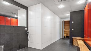 A modern bathroom with grey and white tiles, a wooden bench, and red lockers. - Best Western Royal Star (Älvsjö)