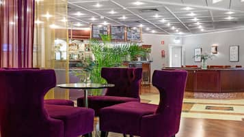 A lobby with purple chairs, a reception desk, and a bar area.