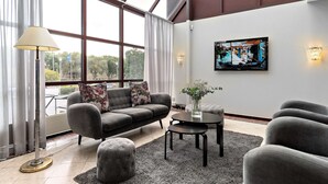 A modern living room with a sofa, armchairs, a coffee table, and a TV mounted on the wall. - Best Western Royal Star (Älvsjö)