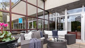 An outdoor seating area with wicker furniture, a round table, and a potted plant. - Best Western Royal Star (Älvsjö)