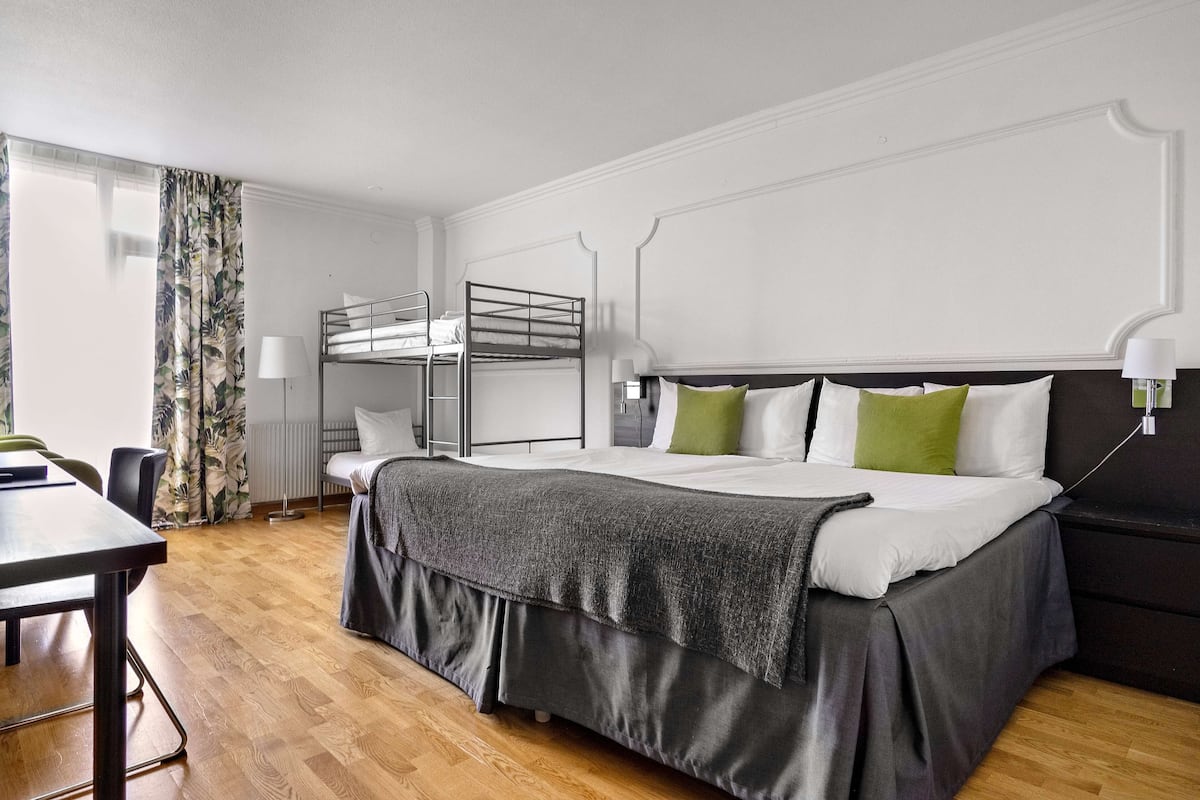 A hotel room with a bunk bed, a desk, and a chair.