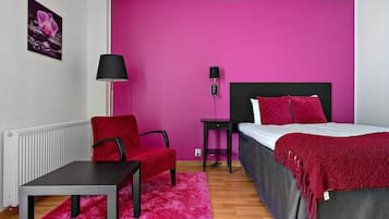 Un dormitorio con cama, una silla, una mesa y una lámpara.