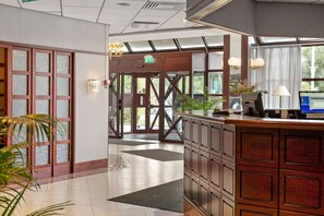 A reception area with a wooden counter, a computer, and a plant. - Best Western Royal Star (Älvsjö)