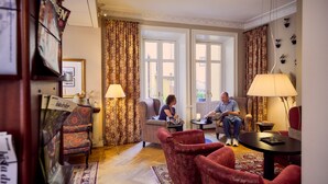 A well-furnished living room with a sofa, armchairs, a coffee table, and a lamp. - Hotel Royal (Gothenburg)