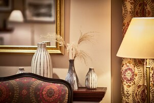 Quarto com uma mesa lateral de madeira que contém três vasos, uma luminária e um espelho emoldurado.